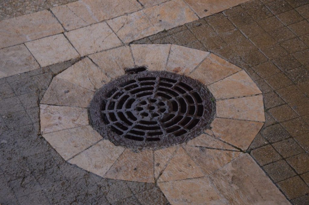 Crafting Captivating Headlines: Your awesome post title goes here Close-up of an intricate iron manhole cover on a paved urban sidewalk.